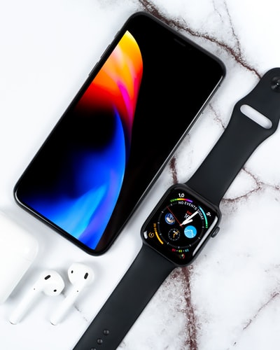 黑色铝表壳苹果手表，黑色运动表带和白色表面的苹果AirPods